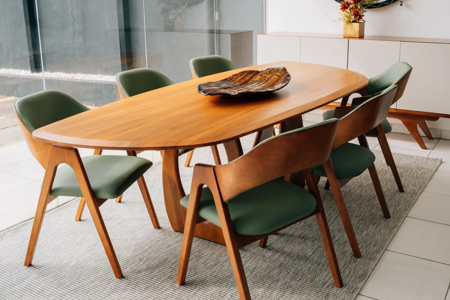 Mesa de jantar oval em madeira maciça com base escultural e cadeiras estofadas em verde-oliva